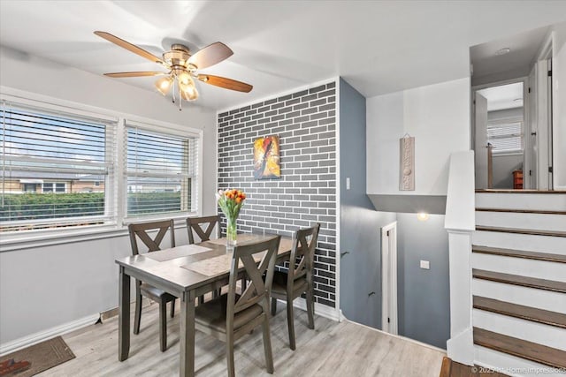 dining area featuring light wood-style floors, stairs, ceiling fan, and baseboards