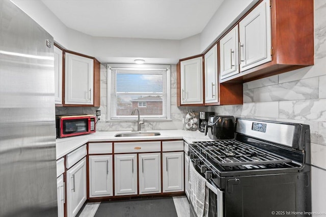 kitchen featuring backsplash, stainless steel appliances, a sink, and light countertops