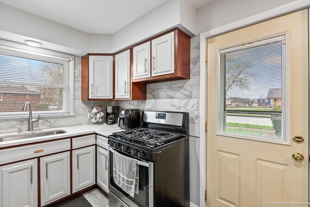 kitchen featuring stainless steel range with gas stovetop, tasteful backsplash, a sink, and light countertops