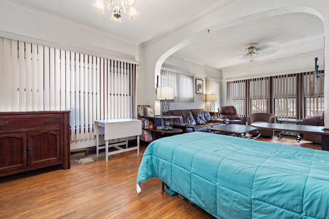 420 N Hebbard St, Joliet, IL 60432 - bedroom featuring arched walkways, wood finished floors, a textured ceiling, ornamental molding, and a chandelier