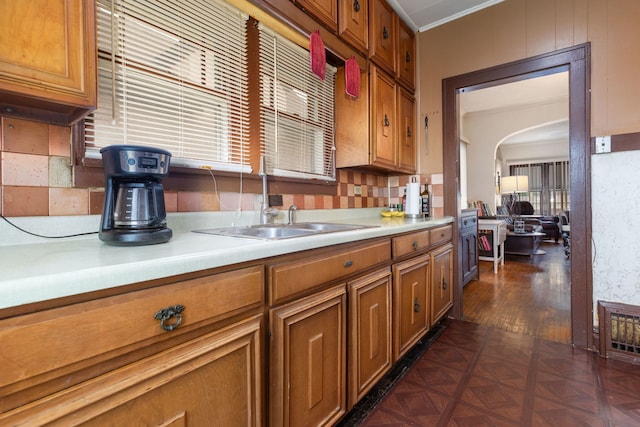 420 N Hebbard St, Joliet, IL 60432 - kitchen featuring light countertops, brown cabinetry, a sink, decorative backsplash, and ornamental molding