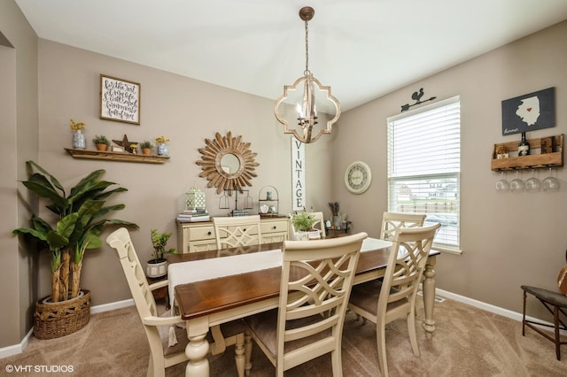 dining space featuring baseboards, light carpet, and a chandelier