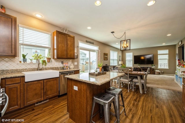 kitchen with dark wood-style flooring, visible vents, stainless steel dishwasher, a sink, and open floor plan