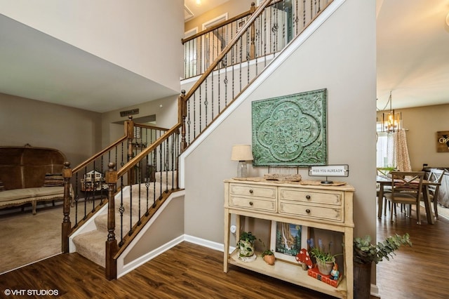 staircase with baseboards, an inviting chandelier, and wood finished floors