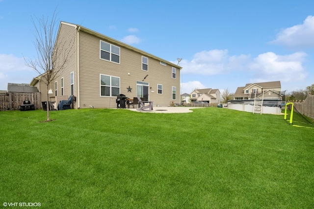 rear view of house featuring fence, a fenced in pool, a patio, and a yard
