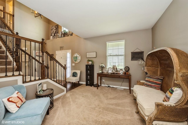 living area featuring baseboards, carpet flooring, and stairs