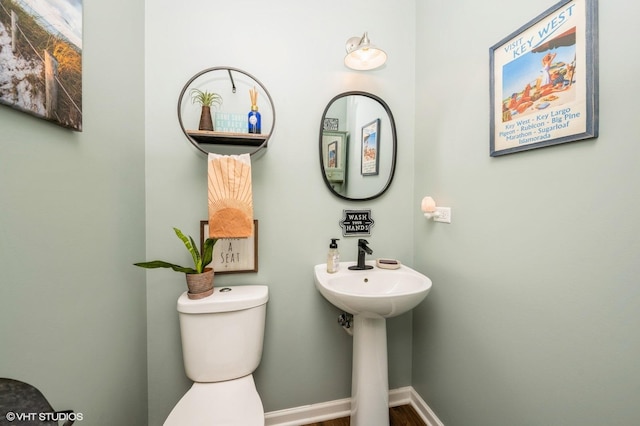 half bathroom featuring baseboards and toilet