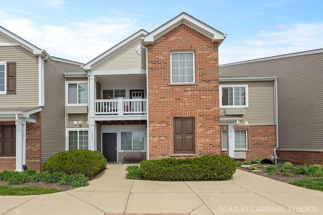 view of property with a balcony and brick siding