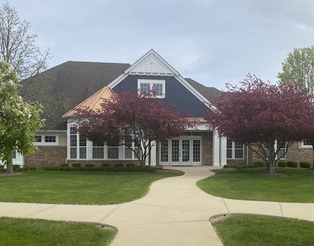 view of front of property featuring brick siding, french doors, and a front lawn