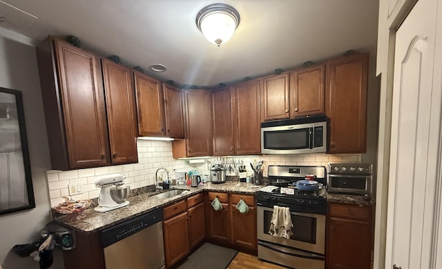 2452 N Lawndale Ave Unit G, Chicago, IL 60647 - kitchen featuring appliances with stainless steel finishes, a sink, dark stone counters, and decorative backsplash