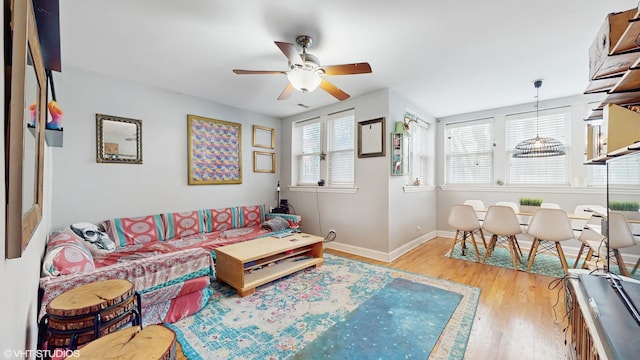 living area featuring a ceiling fan, baseboards, and wood finished floors