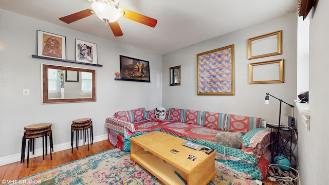 living room featuring a ceiling fan, baseboards, and wood finished floors