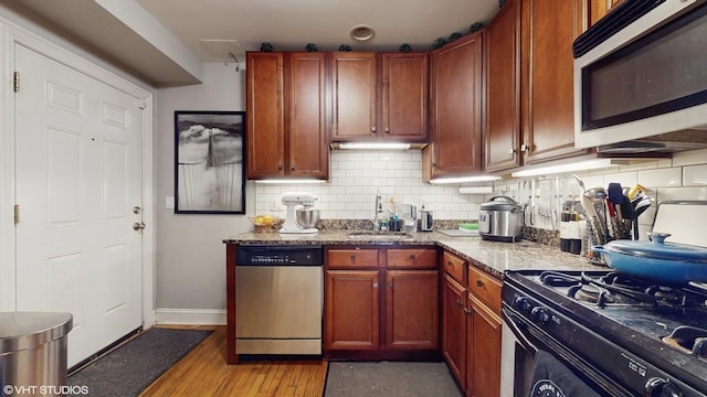 kitchen with a sink, light wood finished floors, baseboards, decorative backsplash, and stainless steel dishwasher