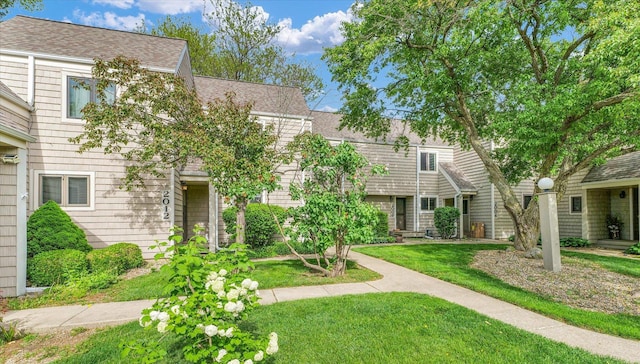 townhome / multi-family property featuring a shingled roof and a front lawn