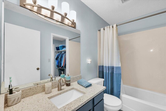 bathroom with shower / tub combo with curtain, vanity, toilet, a textured ceiling, and a spacious closet