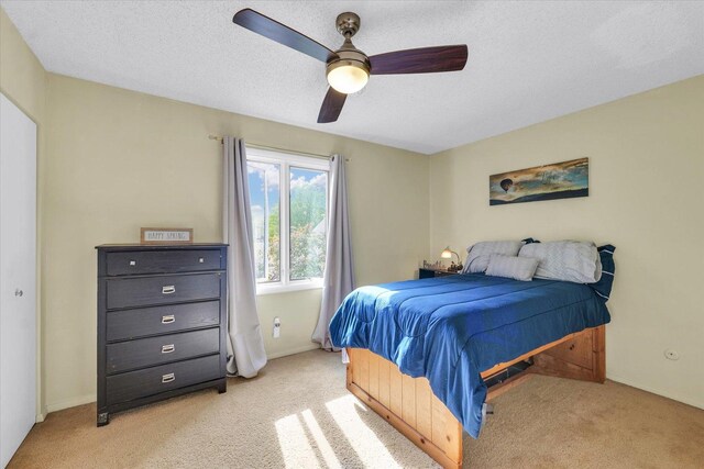 bedroom featuring baseboards, a ceiling fan, a textured ceiling, and light carpet