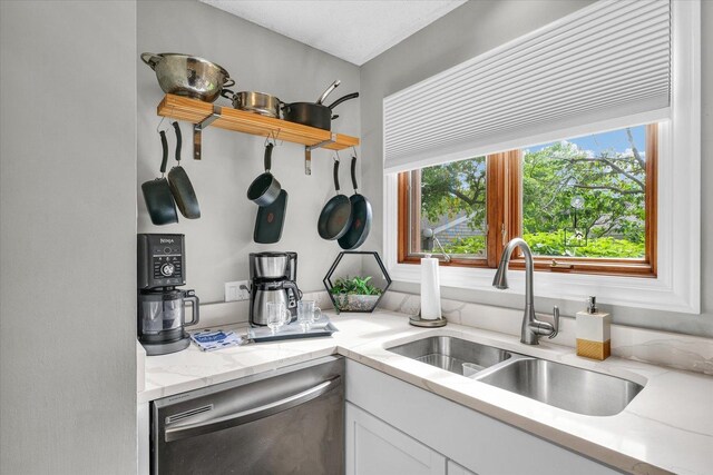 kitchen featuring a sink, dishwasher, white cabinets, and a healthy amount of sunlight