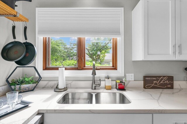 kitchen featuring a sink, white cabinetry, and light stone countertops