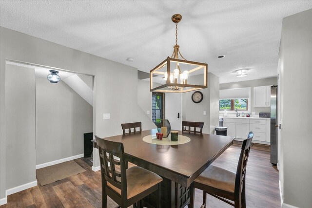 dining space with baseboards, dark wood-style flooring, a textured ceiling, and a chandelier
