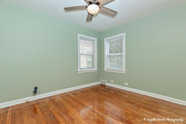 spare room with ceiling fan, baseboards, visible vents, and wood finished floors