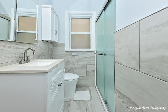 bathroom featuring vanity, toilet, marble finish floor, tile walls, and decorative backsplash