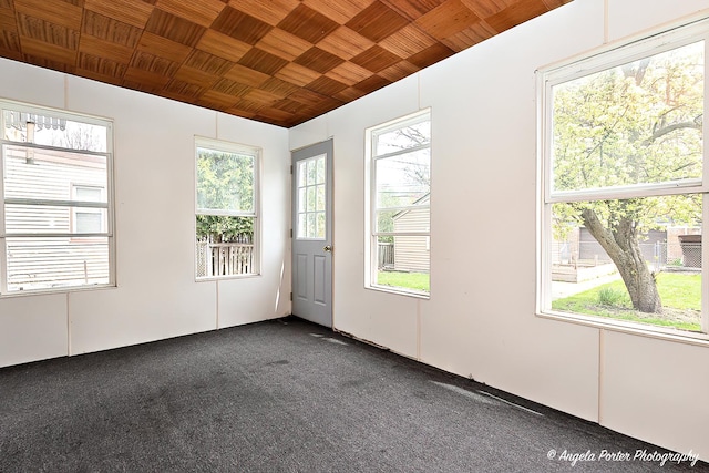 empty room with wood ceiling and dark colored carpet