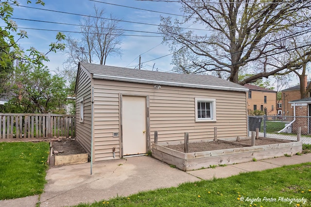view of outbuilding with fence, an outdoor structure, and a vegetable garden