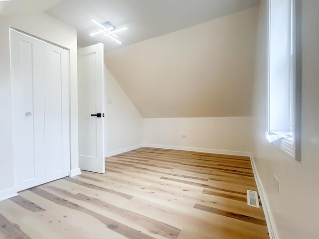 additional living space featuring lofted ceiling, visible vents, baseboards, and light wood-style floors