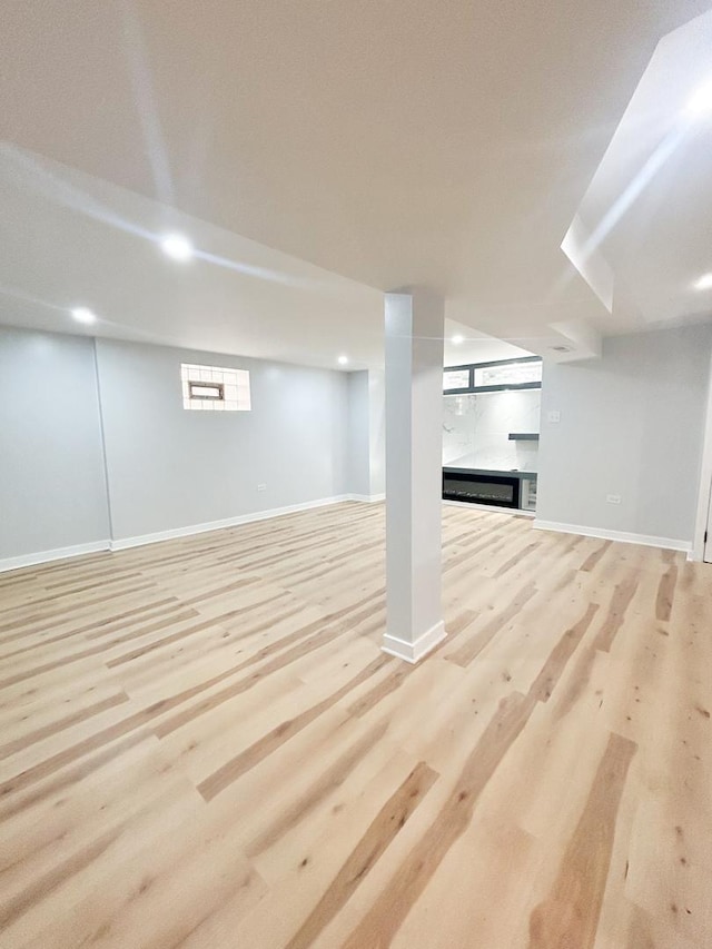 below grade area featuring baseboards, light wood-style floors, and a fireplace