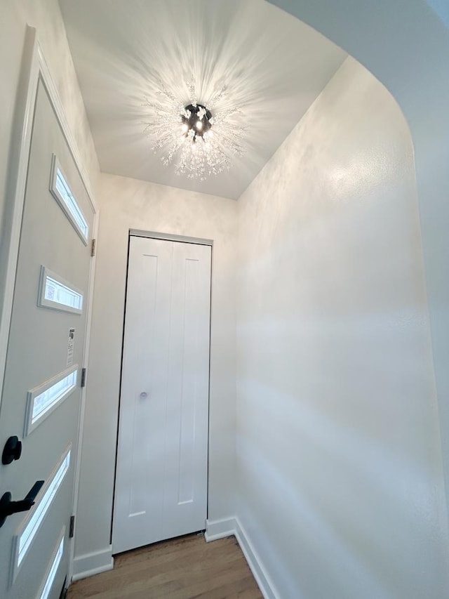 entryway with arched walkways, wood finished floors, and baseboards