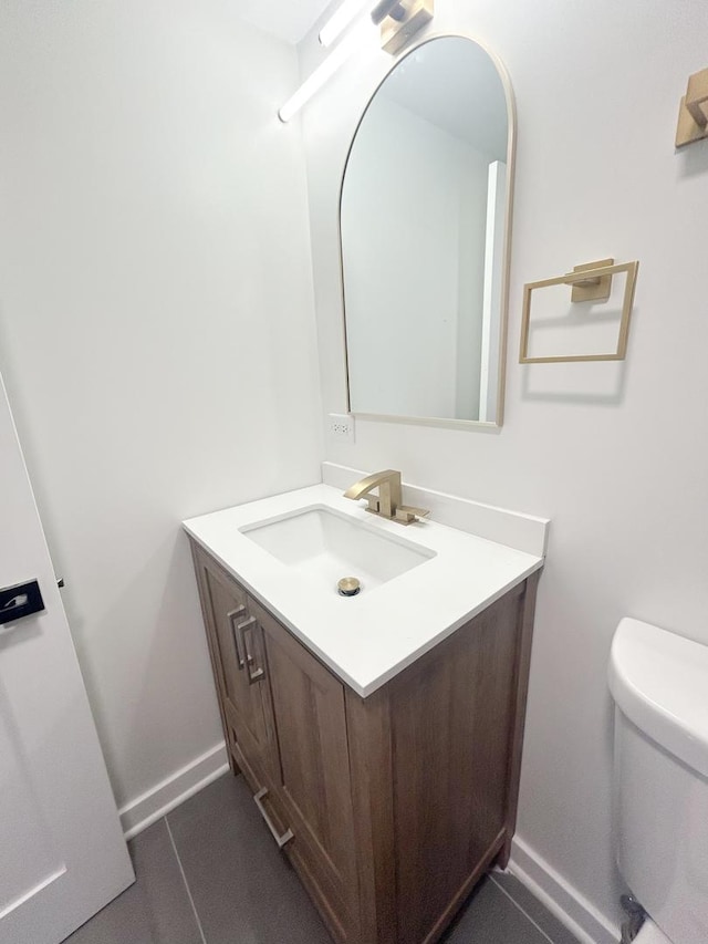 half bath with toilet, vanity, and baseboards