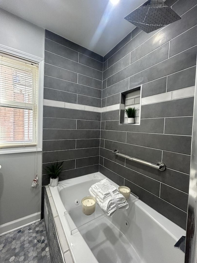 bathroom with a tub with jets, tiled shower, and baseboards