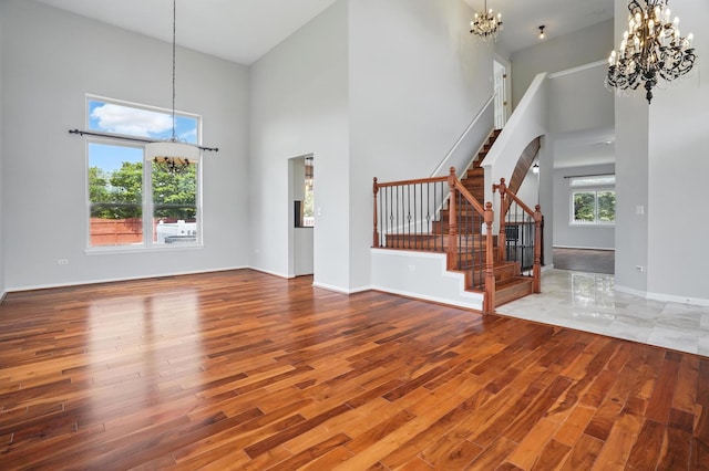 122 Periwinkle Ln, Bolingbrook, IL 60490 - unfurnished living room featuring a chandelier, a high ceiling, wood finished floors, stairway, and baseboards