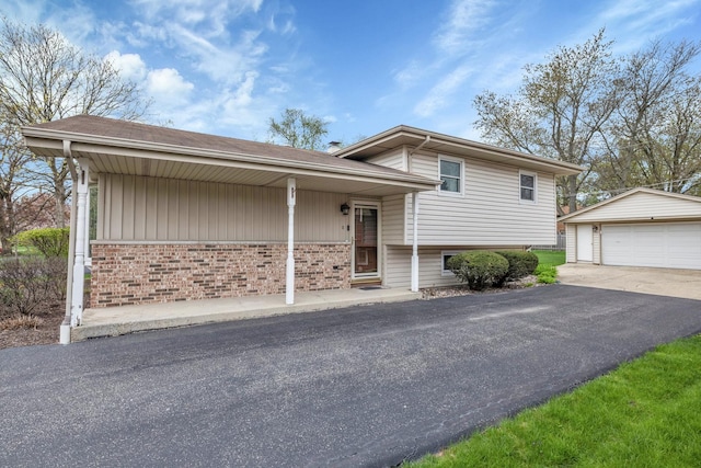 split level home with a detached garage, brick siding, and an outdoor structure