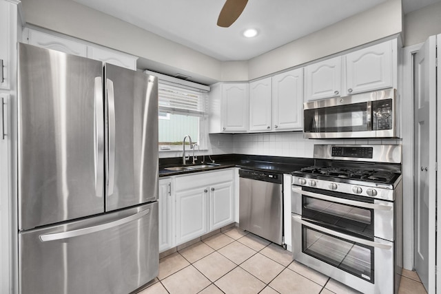 kitchen featuring a sink, light tile patterned floors, dark countertops, white cabinets, and appliances with stainless steel finishes