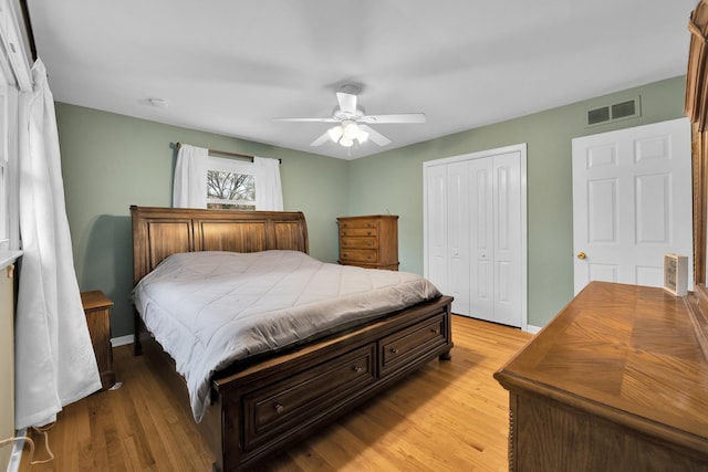 bedroom with light wood-style floors, a closet, ceiling fan, visible vents, and baseboards