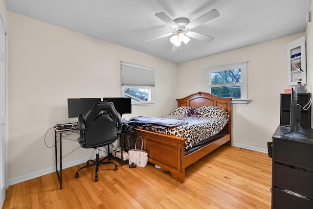 bedroom with light wood-style floors, ceiling fan, and baseboards