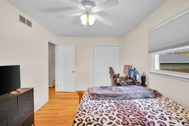 bedroom featuring a closet, a ceiling fan, visible vents, light wood-style flooring, and baseboards