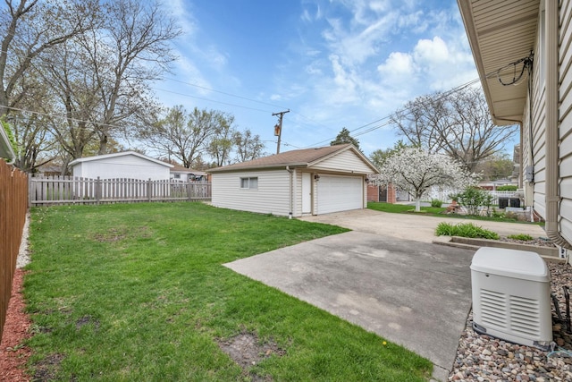 view of yard with fence, a detached garage, a patio area, and an outbuilding