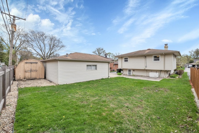 rear view of house featuring an outbuilding, a lawn, a fenced backyard, and a patio area