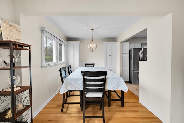 dining area featuring a chandelier, baseboards, and light wood-style floors