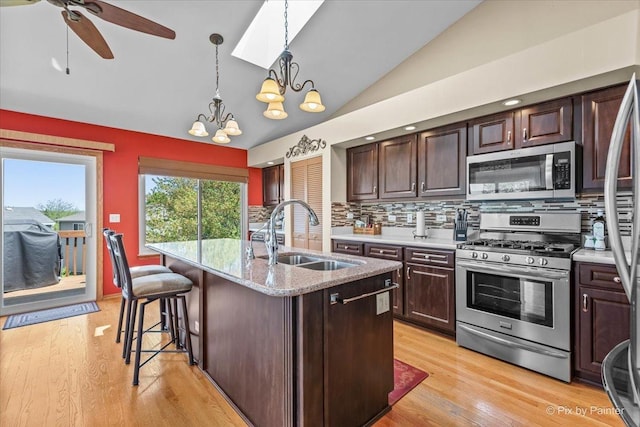 kitchen with appliances with stainless steel finishes, a sink, lofted ceiling, decorative backsplash, and dark brown cabinetry