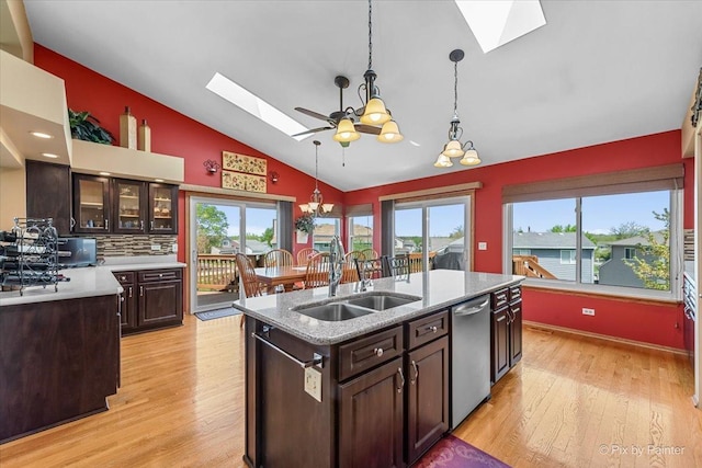 kitchen with a skylight, a sink, vaulted ceiling, dishwasher, and a chandelier