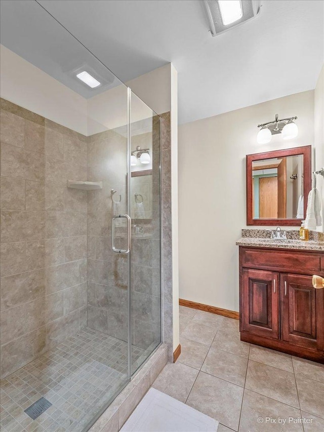full bath featuring a shower stall, tile patterned floors, baseboards, and vanity