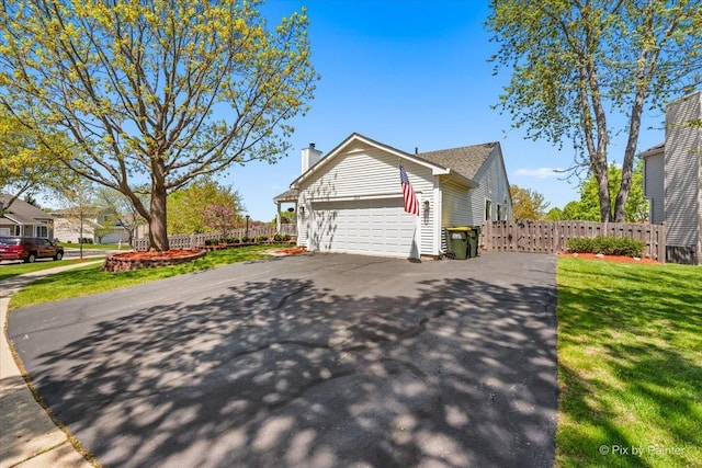 view of side of home with asphalt driveway, a garage, and a chimney