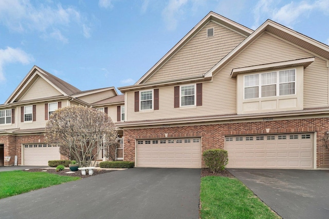 townhome / multi-family property with an attached garage, driveway, and brick siding