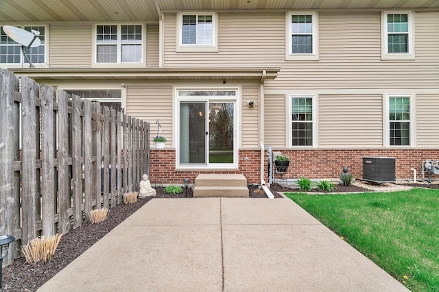 entrance to property with brick siding, central AC, fence, and a patio area