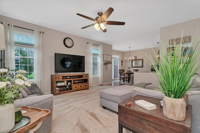 living area with baseboards, carpet, and ceiling fan with notable chandelier