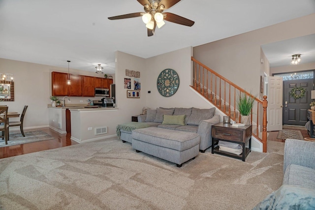 living room with stairway, carpet, ceiling fan with notable chandelier, and visible vents