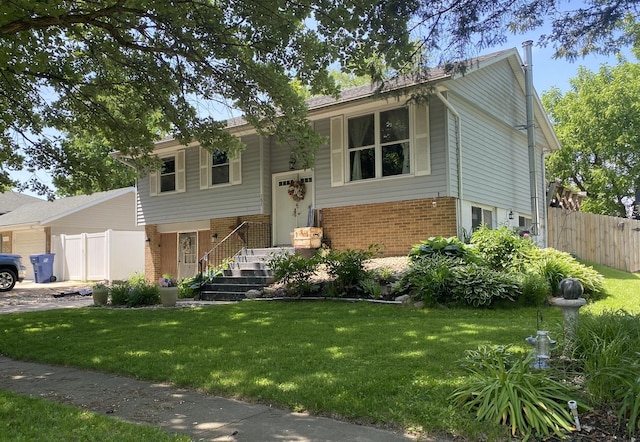 raised ranch with brick siding, fence, and a front yard